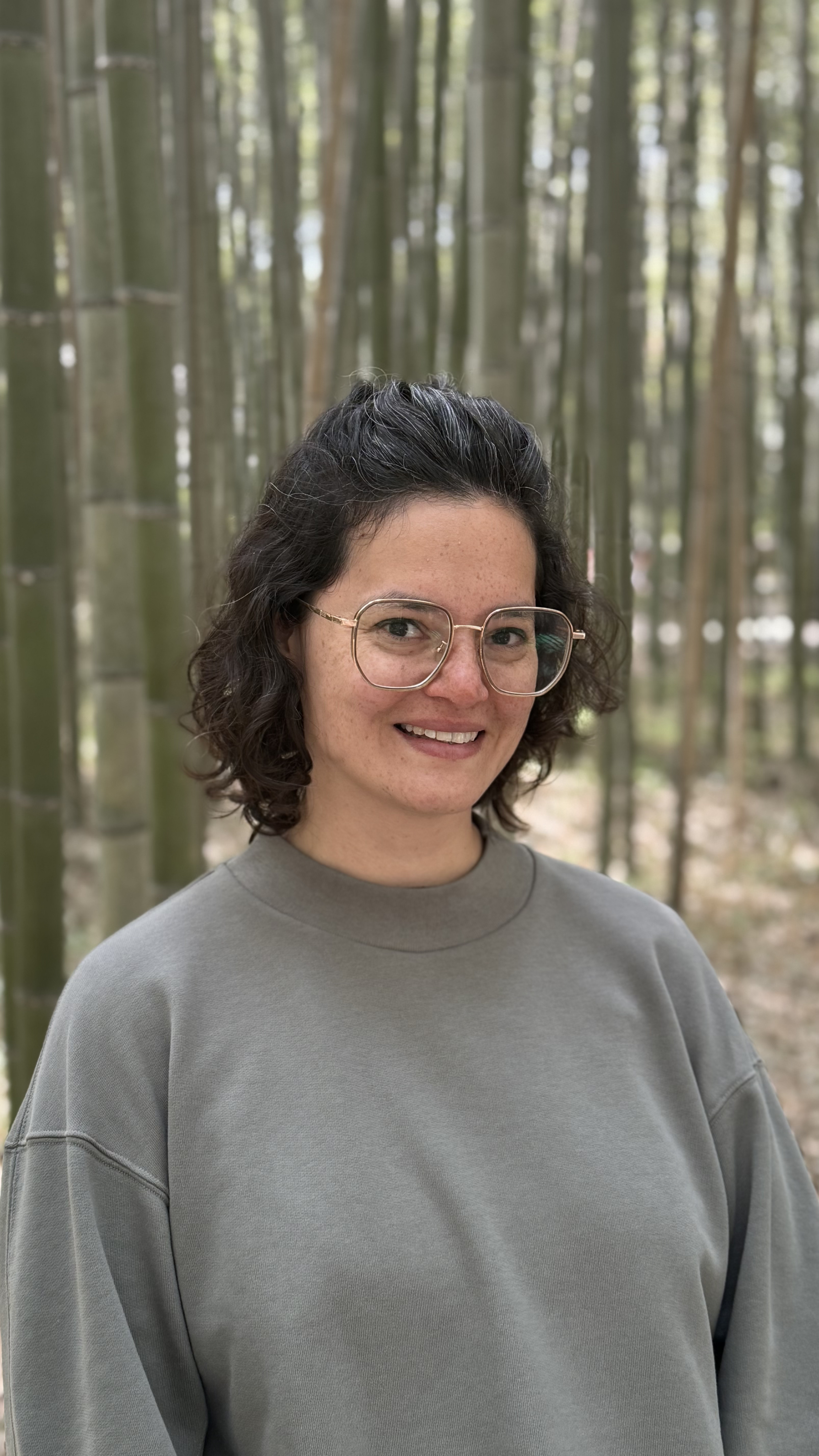 Mujer de anteojos y cabello castaño ondulado sonriendo