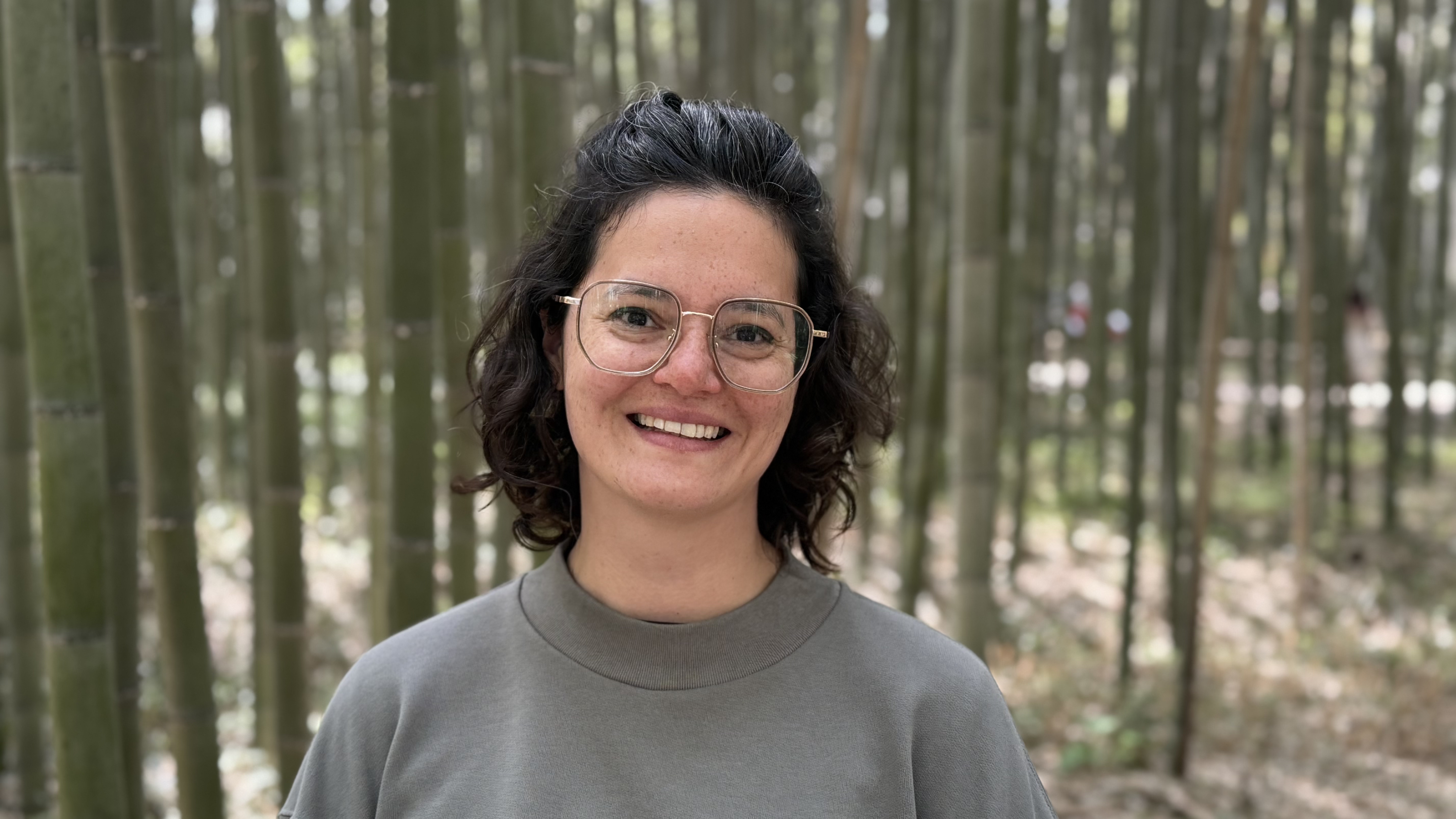 Mujer de anteojos y cabello castaño ondulado sonriendo